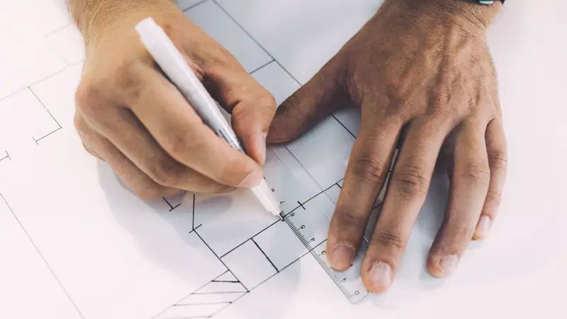 An architect's scale ruler resting on a technical drawing