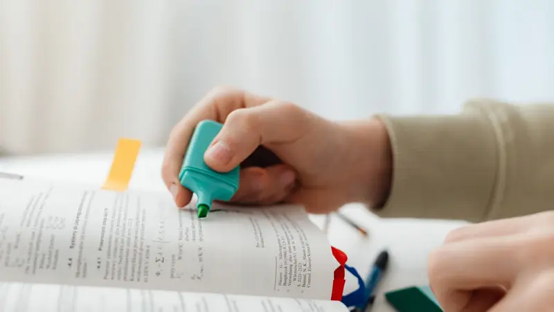 A student highlighting passages in a textbook