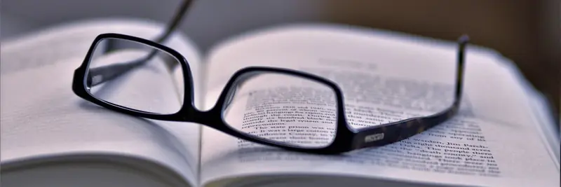 Reading glasses resting on a printed page of dense text