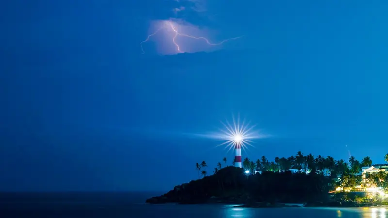 A lighthouse beam sweeping across the sea at night