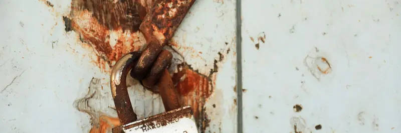 A heavy metal padlock securing a latch